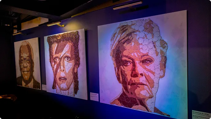 Gallery wall with creative biscuit art portraits of Judi Dench, David Bowie, and Trevor McDonald, made using McVitie’s Chocolate Digestives