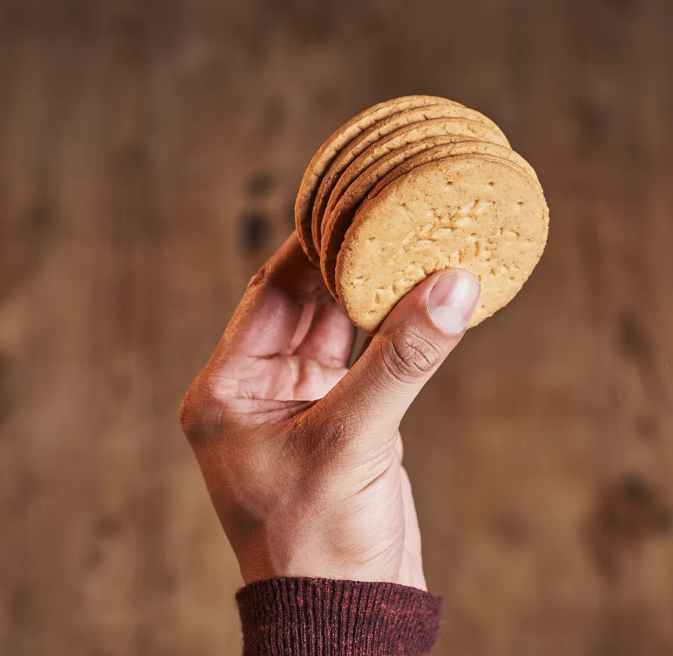 A hand holding a stack of McVite's Digestives